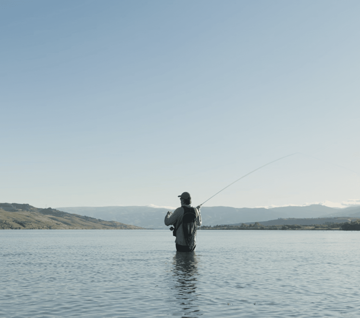 Scott, owner and lead guide, casting a fly rod on a glassy South Island lake